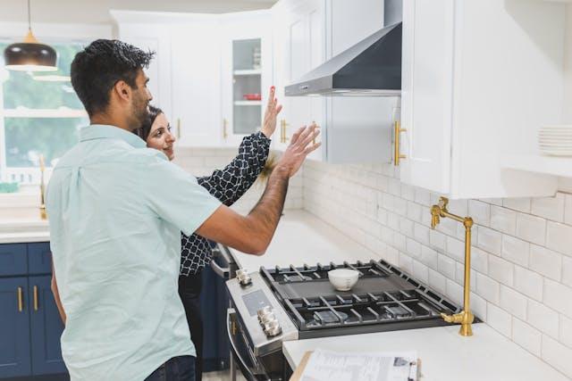 Two people inspecting a stove fan